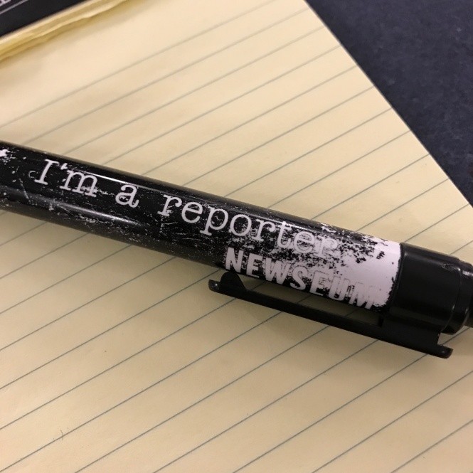 "I'm a reporter" ink pen from the Newseum on a yellow legal pad.