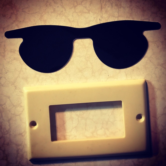 Light switch cover makes a mouth and, together with the little plastic sunglasses insert from the eye doctor, makes a face.