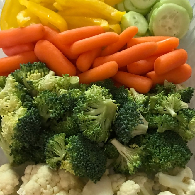 Chopped veggies, including cauliflower, broccoli, carrots, cucumbers, and yellow peppers.